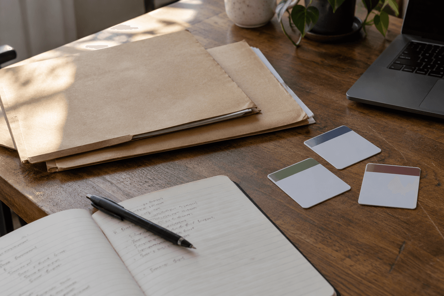 Photorealistic AI-generated editorial image of paper folders, a notebook, and three unbranded access cards on a wooden office desk. Conceptual visual for separate responsibilities and private documents; not real client records or documentary evidence.